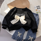 Tenue élégante pour fille avec une touche moderne - haut noir avec nœud papillon élégant et jean plissé attrayant